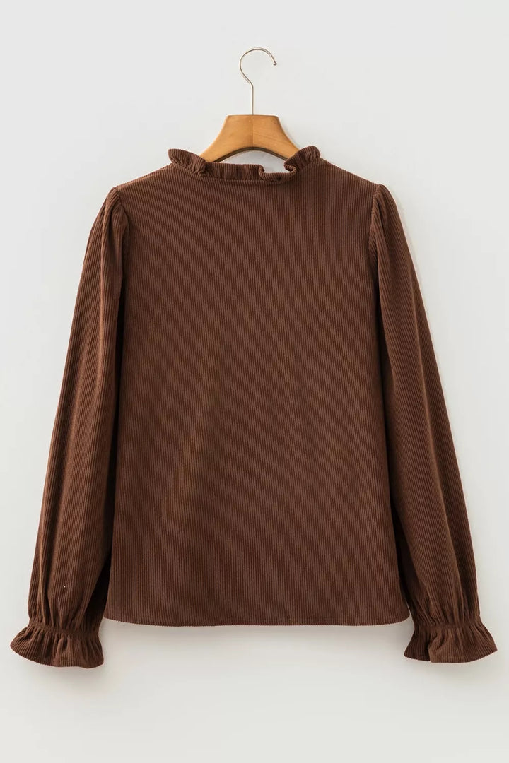 Back of the dark brown corduroy blouse on a hanger with ruffle collar