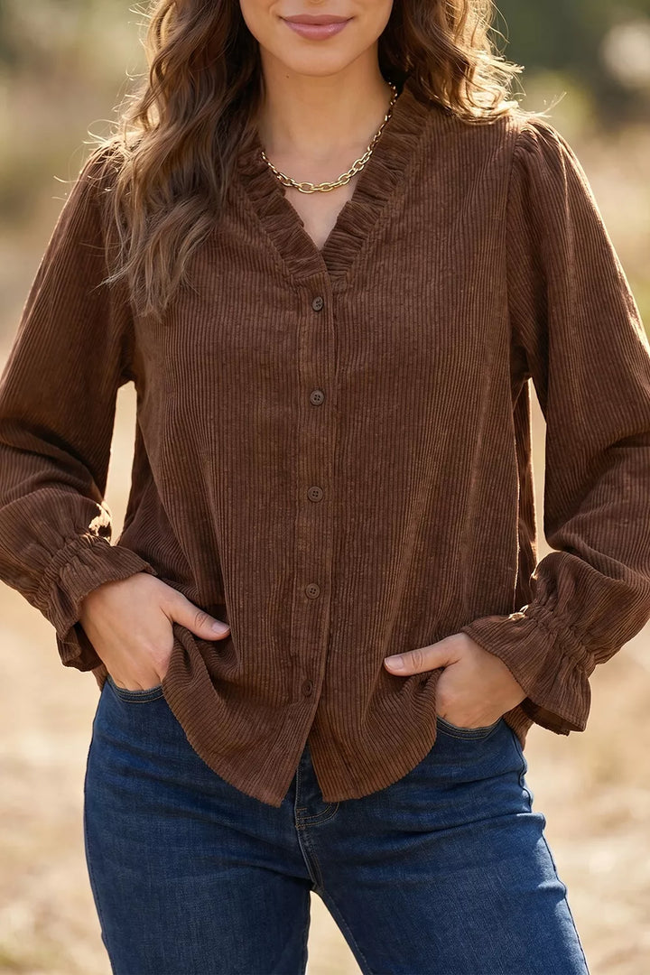 Dark brown ruffle neck button up blouse styled with blue jeans outdoors