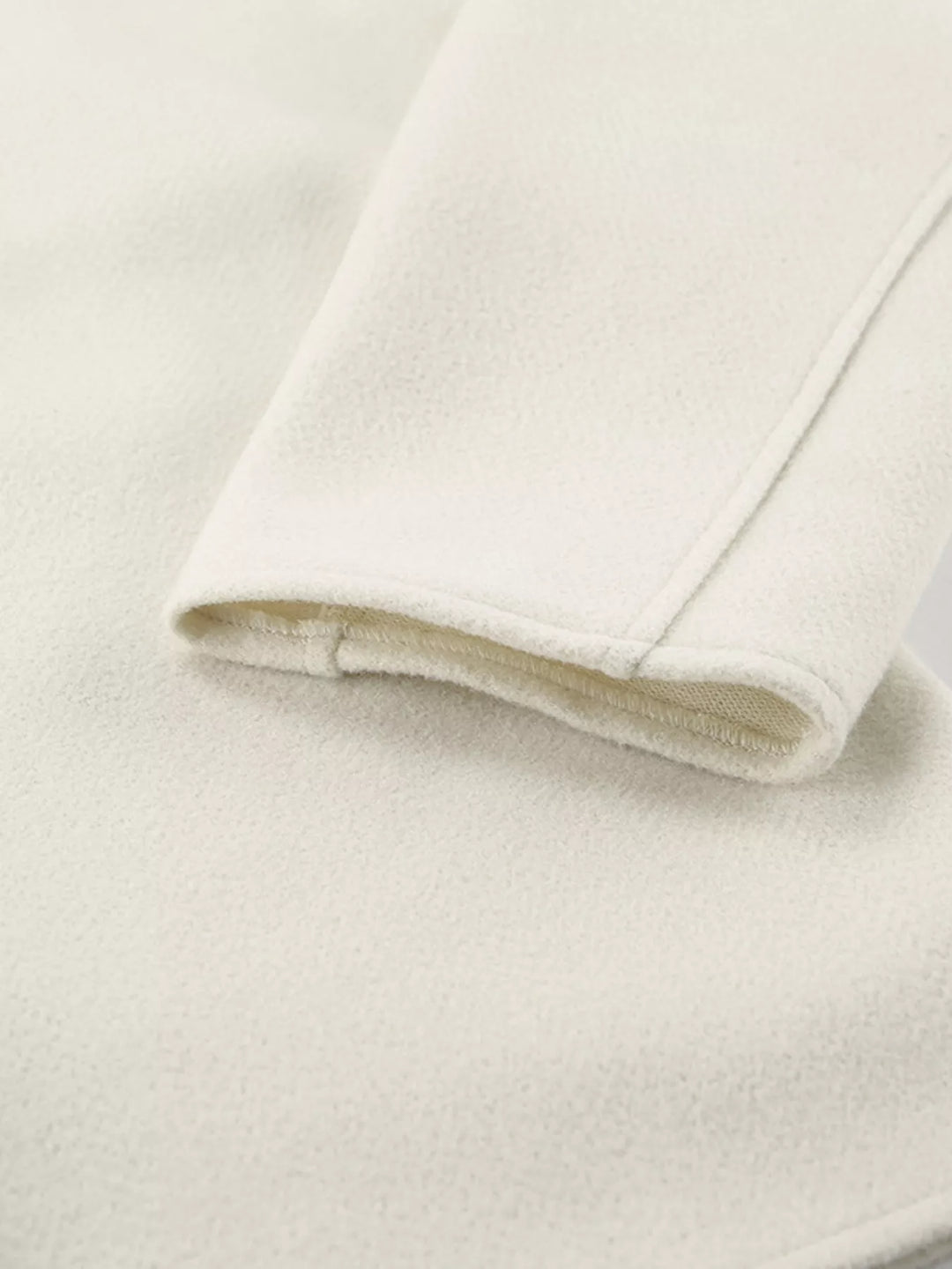 Close-up of the ivory cropped jacket sleeve cuff