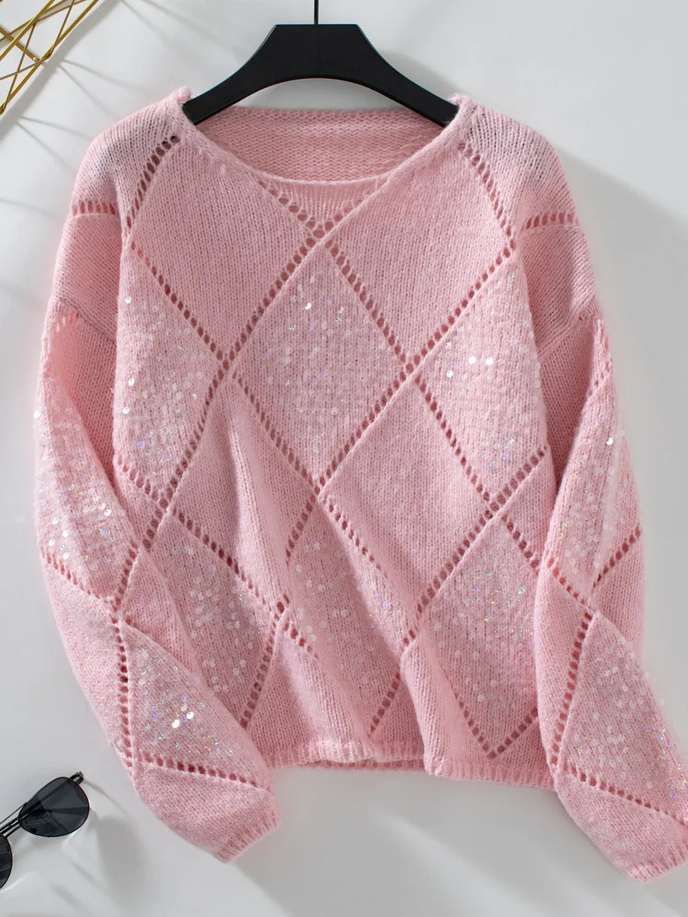 Dusty pink cropped sweater with openwork diamond knit, hanging flat on a hanger