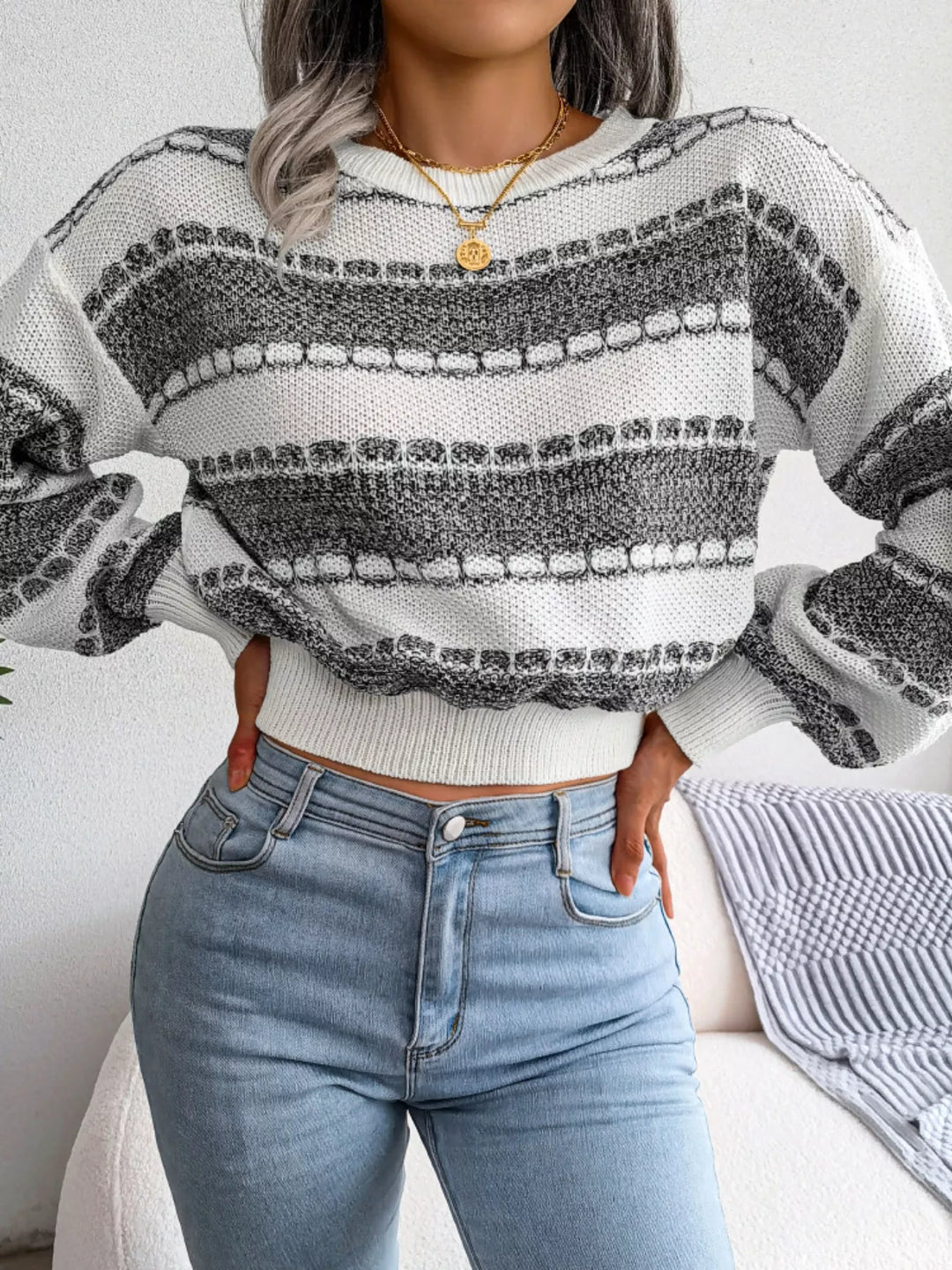 Dark gray striped crew neck sweater with hands on hips and jeans