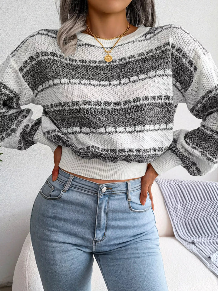 Dark gray striped crew neck sweater with hands on hips and jeans