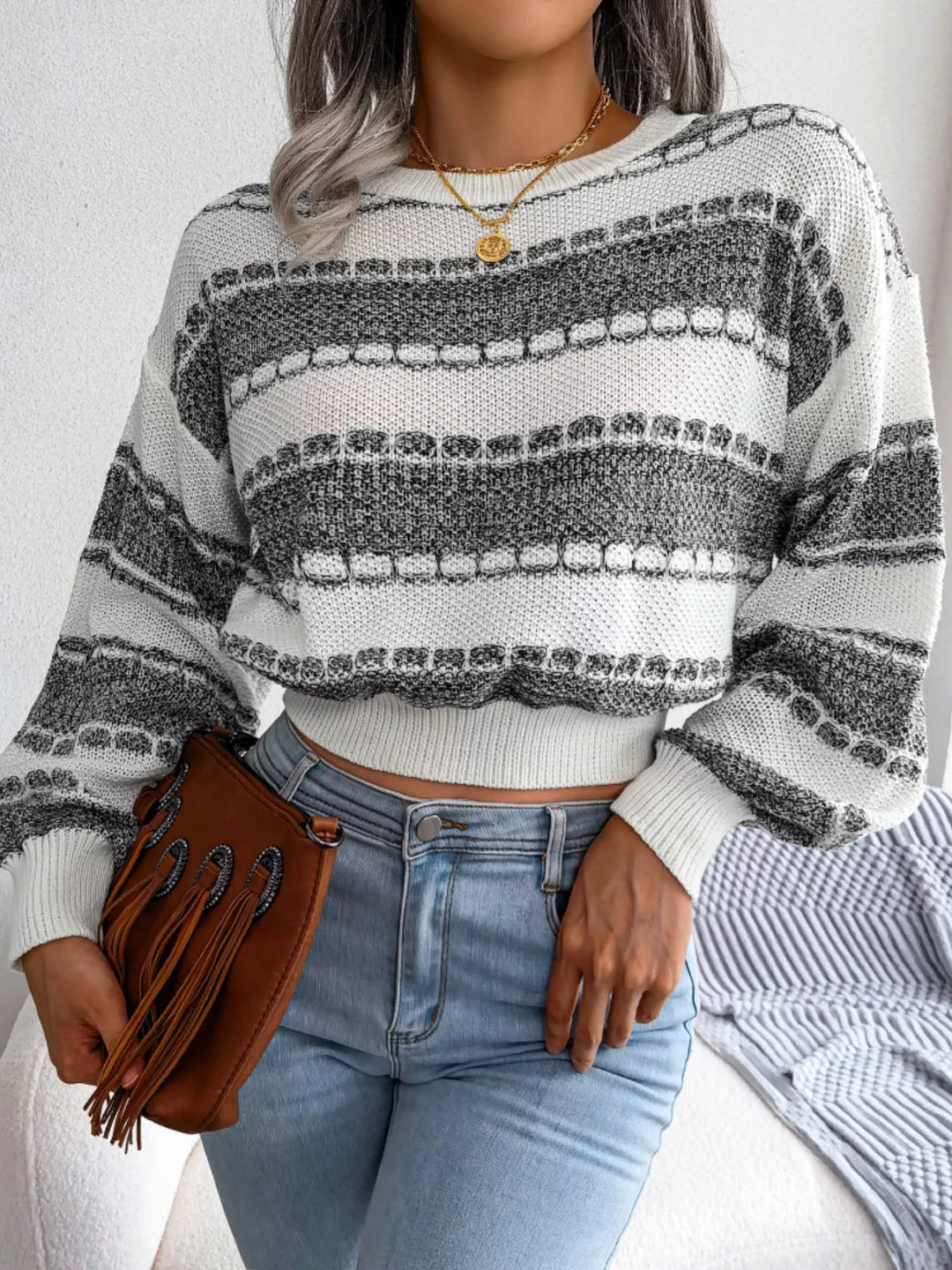 Dark gray cropped sweater styled with a brown fringe clutch