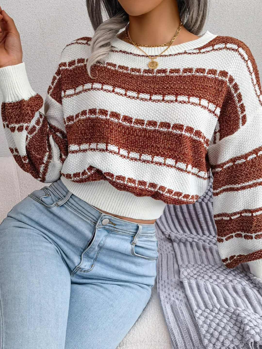 Rust wide stripe crew neck cropped sweater with hand touching the sleeve