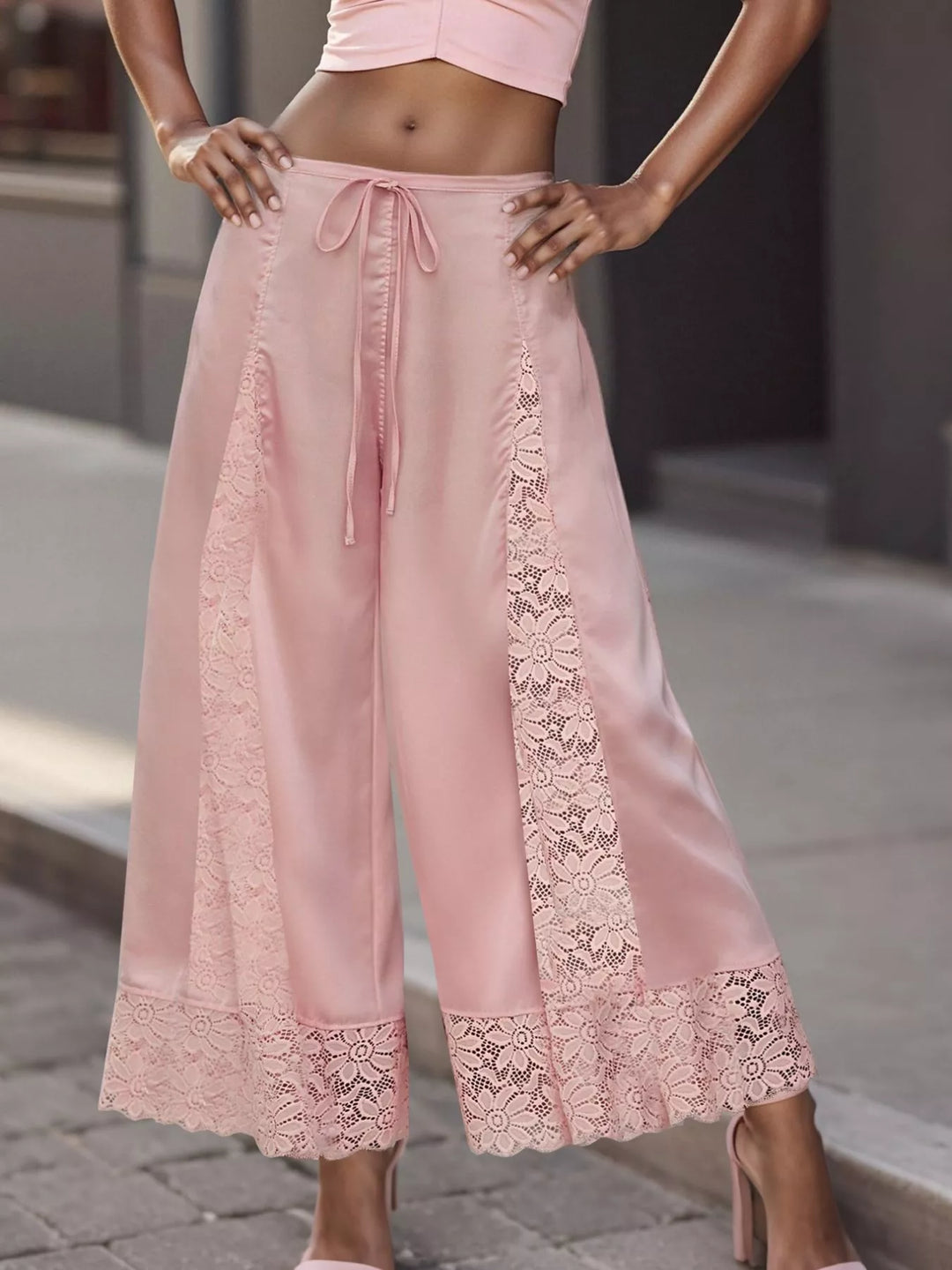 Pink cropped wide leg pants with drawstring waist and lace panel, front view