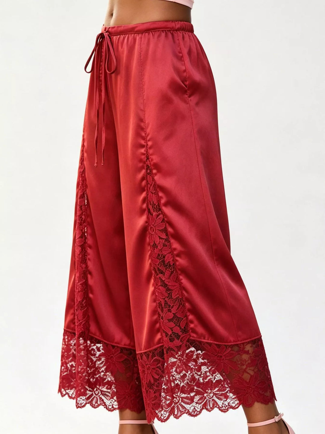 Side view of the red drawstring pants showing the ruched seam and lace hem