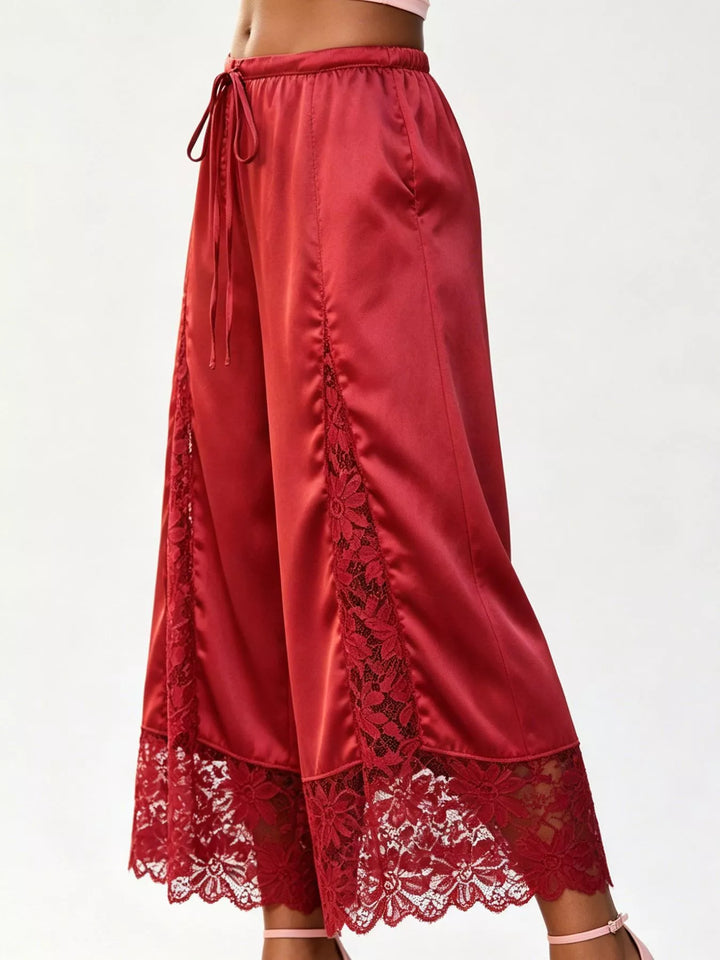 Side view of the red drawstring pants showing the ruched seam and lace hem