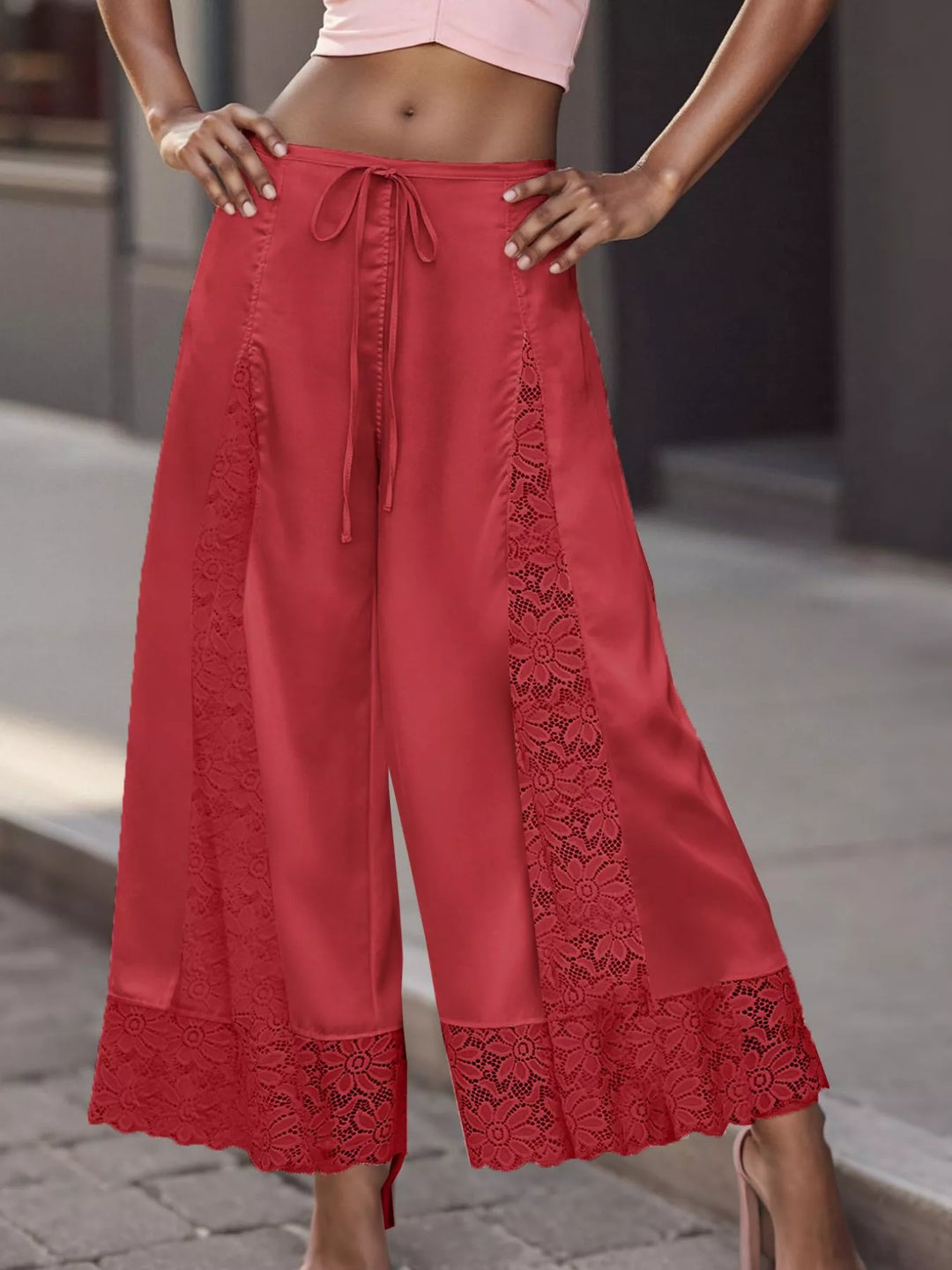 Red cropped lace panel pants worn with a pink top and strappy heels