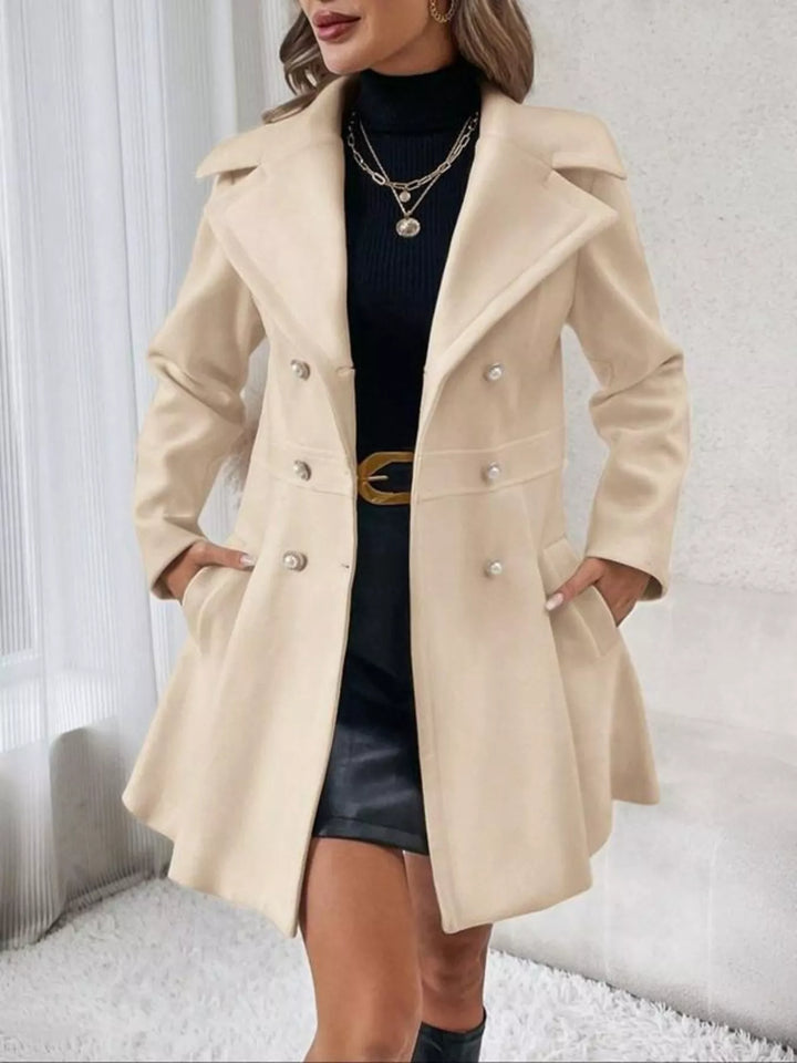 Beige double breasted coat with notch lapel, belted look over a leather skirt