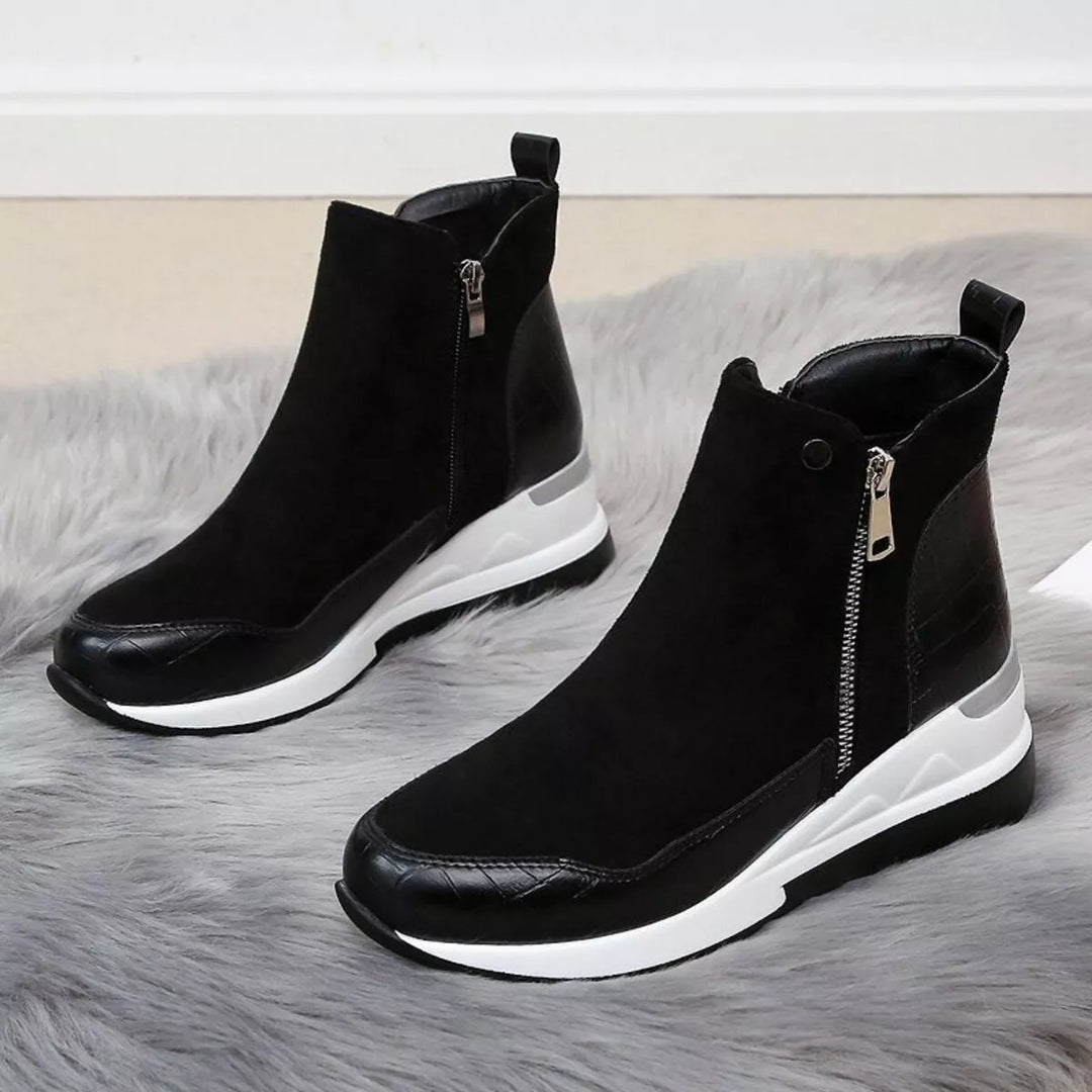 Women's fall boots in black, chunky wedge platform with side zip, pair on a fluffy rug