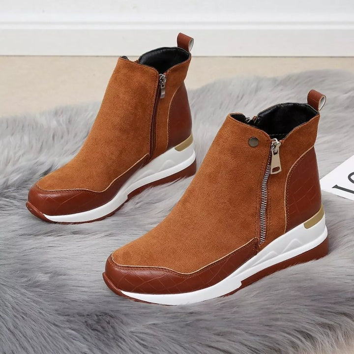 Pair of cognac wedge boots with white platform sole on a gray rug