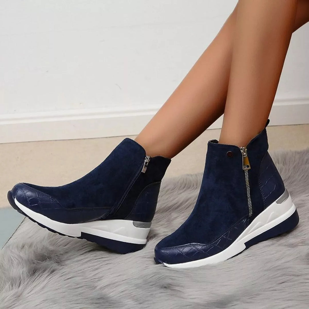 Navy chunky wedge platform boots with side zip, worn on a fluffy rug