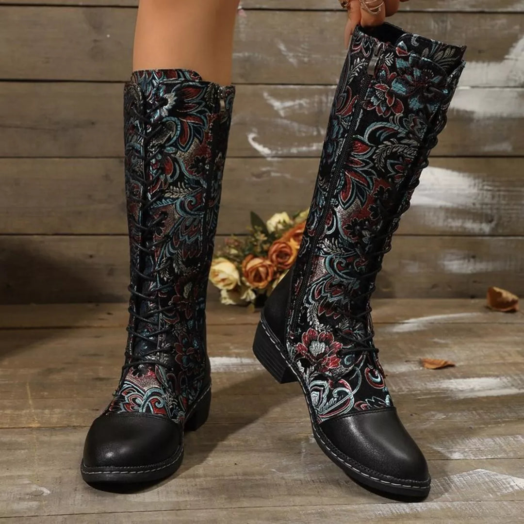Women's fall boots in black, lace up mid calf with embroidered florals, on a wood floor