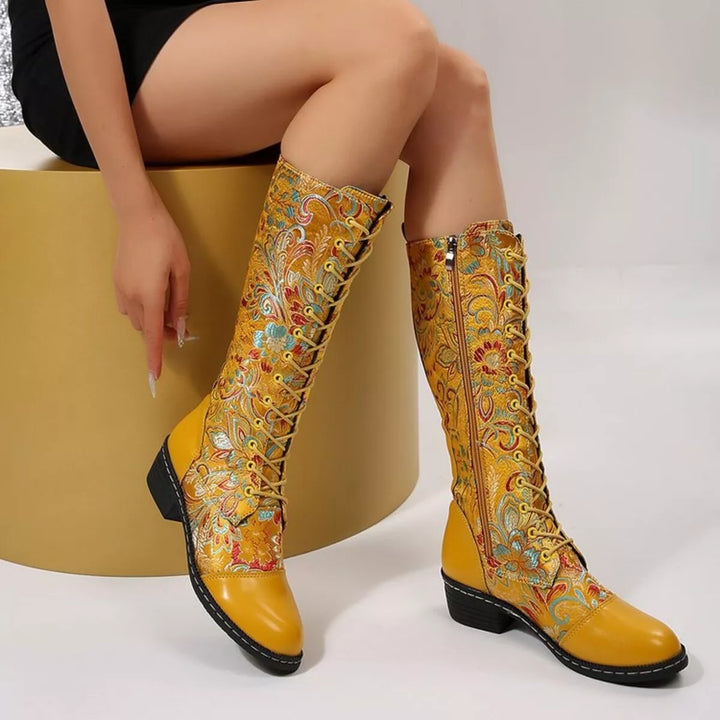 Yellow lace up mid calf boots with embroidered florals, worn seated with a side zipper