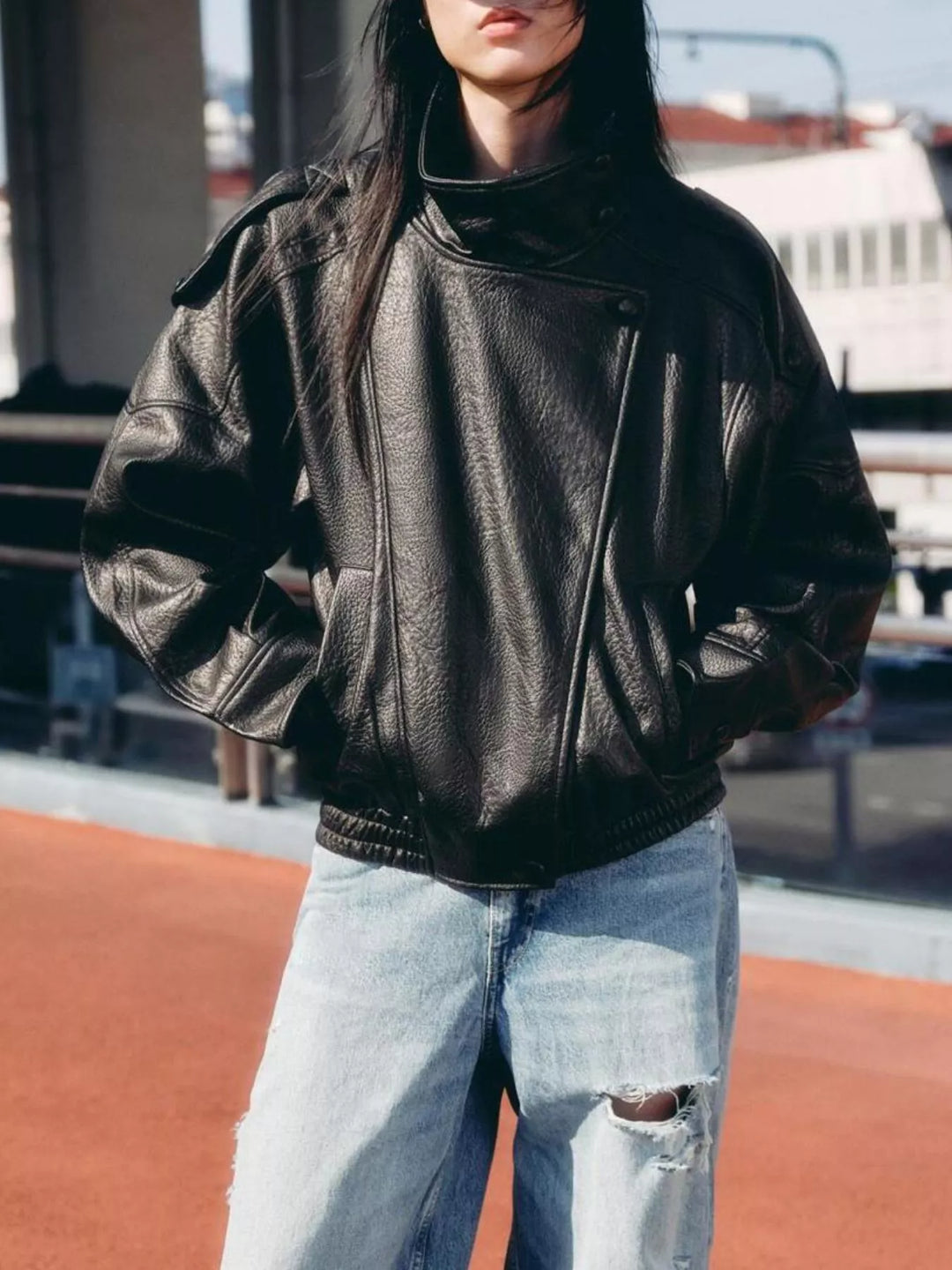 Women's black oversized moto fall jacket with funnel collar and zip, styled with jeans