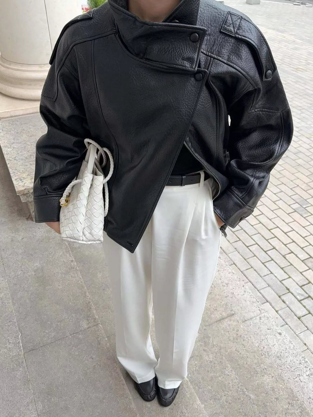 Black funnel collar zip jacket styled with white pants and a clutch
