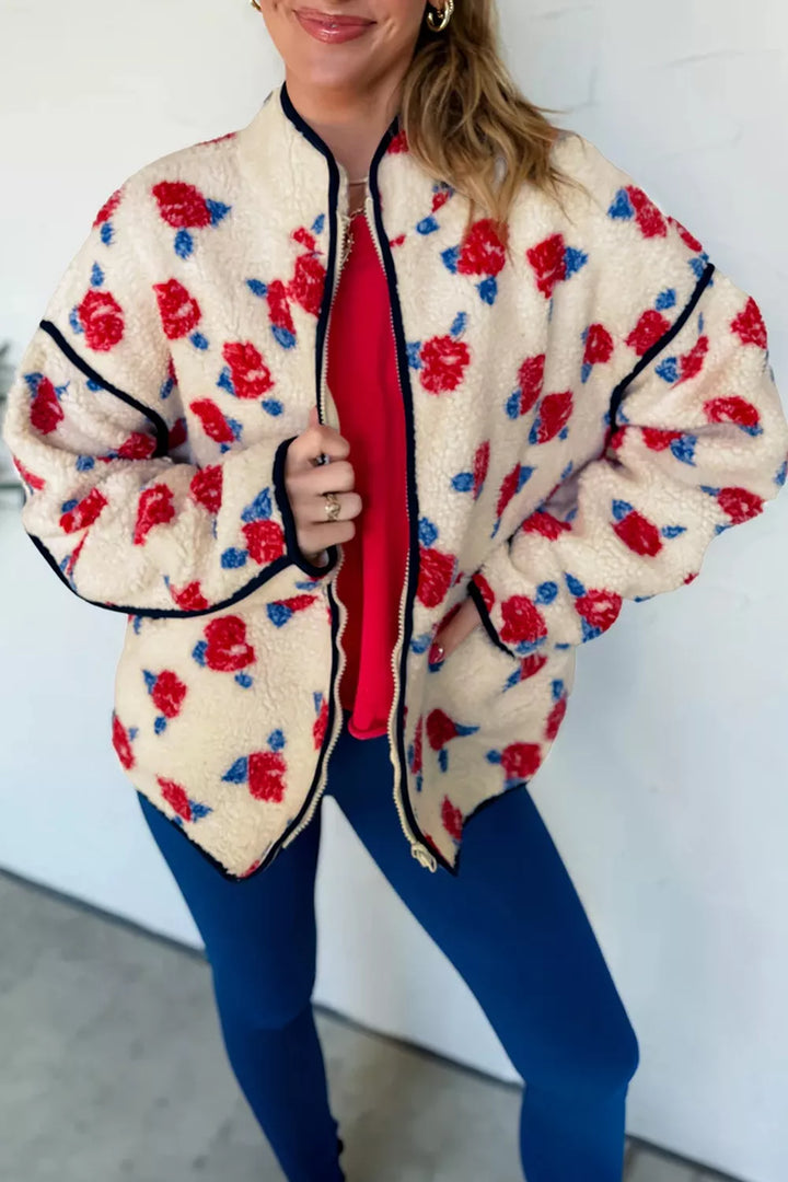 Cream floral zip front jacket styled over a red top and blue pants