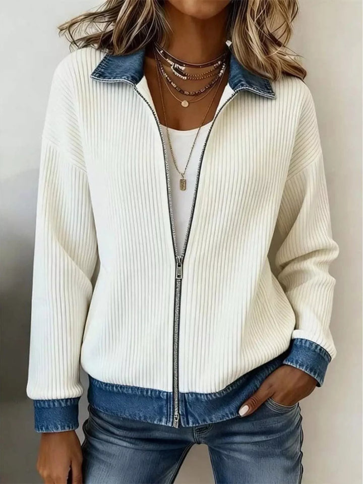 Close-up of white ribbed knit jacket zipper and denim trim at the hem