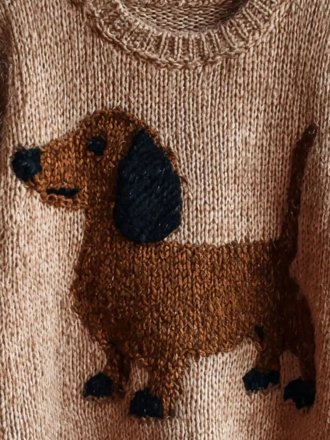 Close-up of the dachshund pattern on the tan chunky knit crew neck sweater