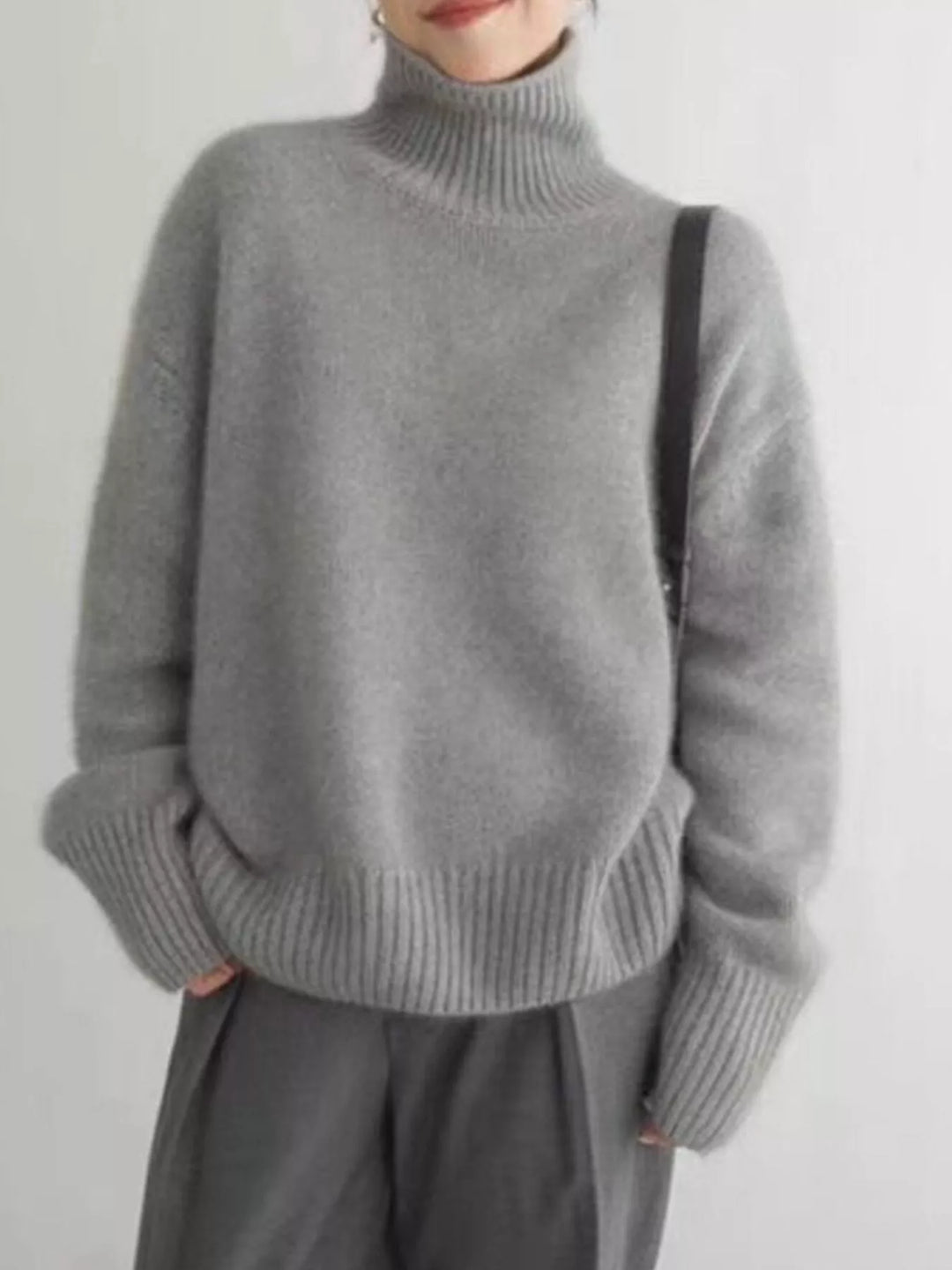 Gray fuzzy turtleneck sweater with dropped shoulders, front view on model