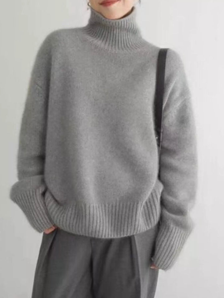 Gray fuzzy turtleneck sweater with dropped shoulders, front view on model