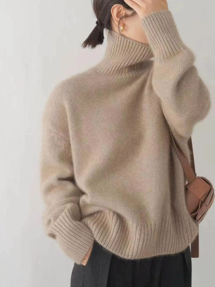 Sand fuzzy turtleneck sweater with raised hand at collar, front view