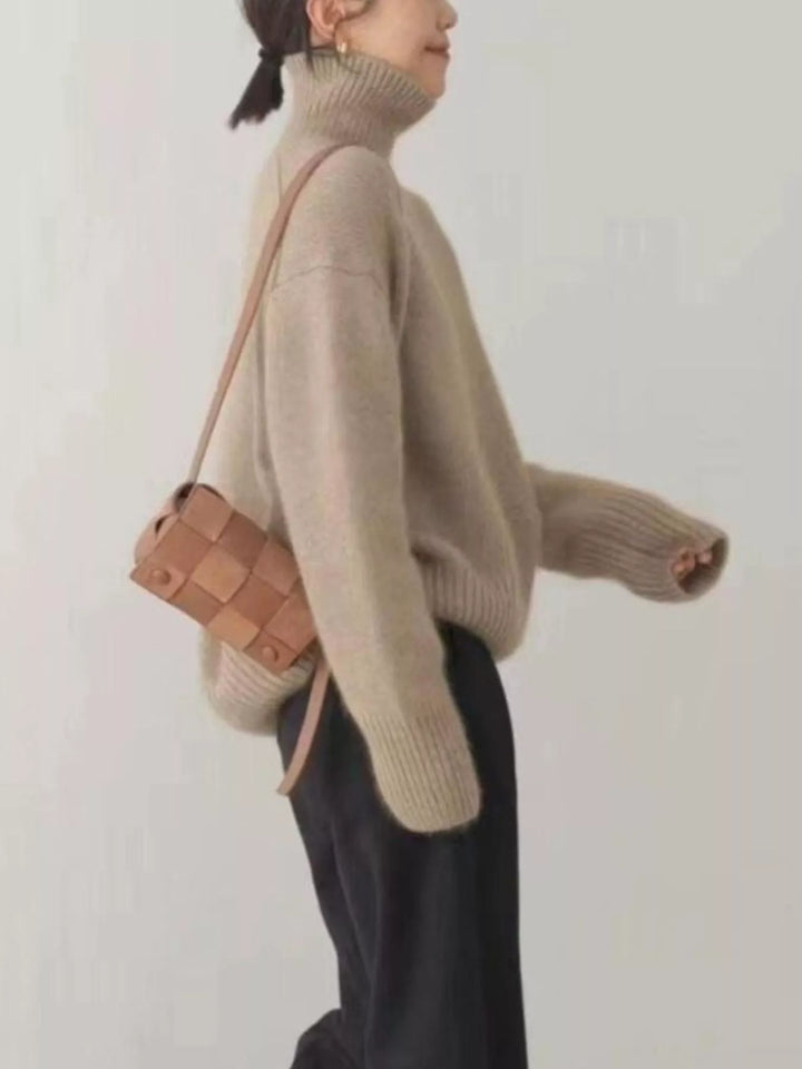 Side view of the sand turtleneck sweater with a woven crossbody bag