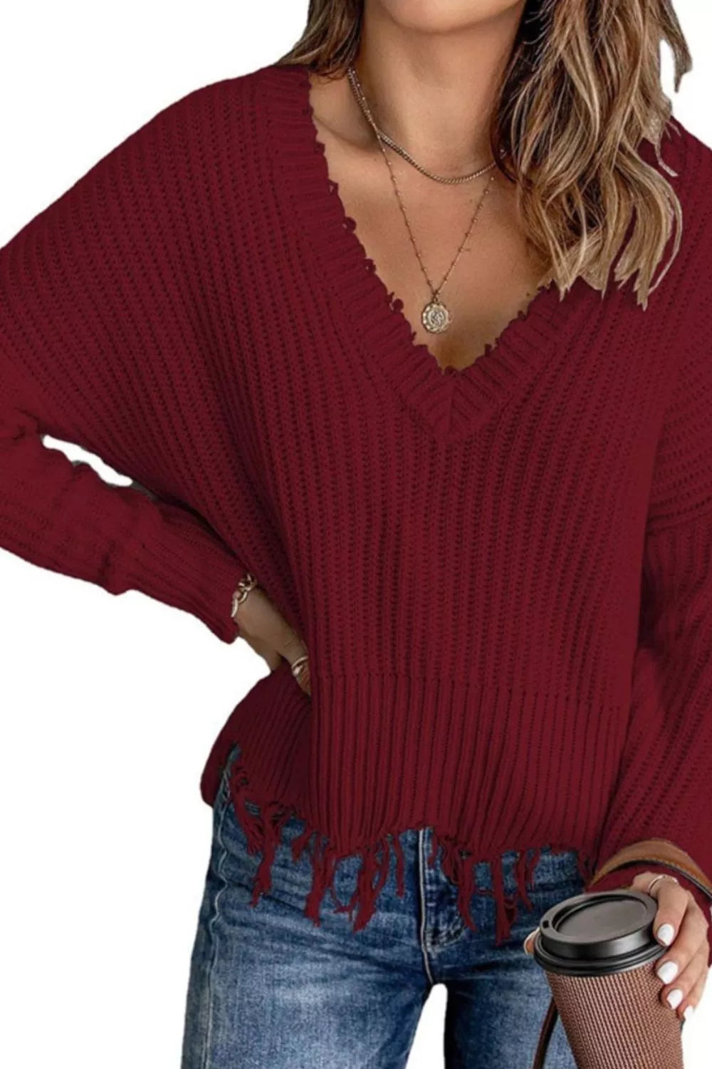 Burgundy v-neck ribbed sweater with frayed hem and hand on hip