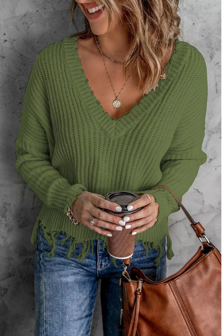 Olive green v-neck sweater with frayed hem, holding a coffee and brown bag