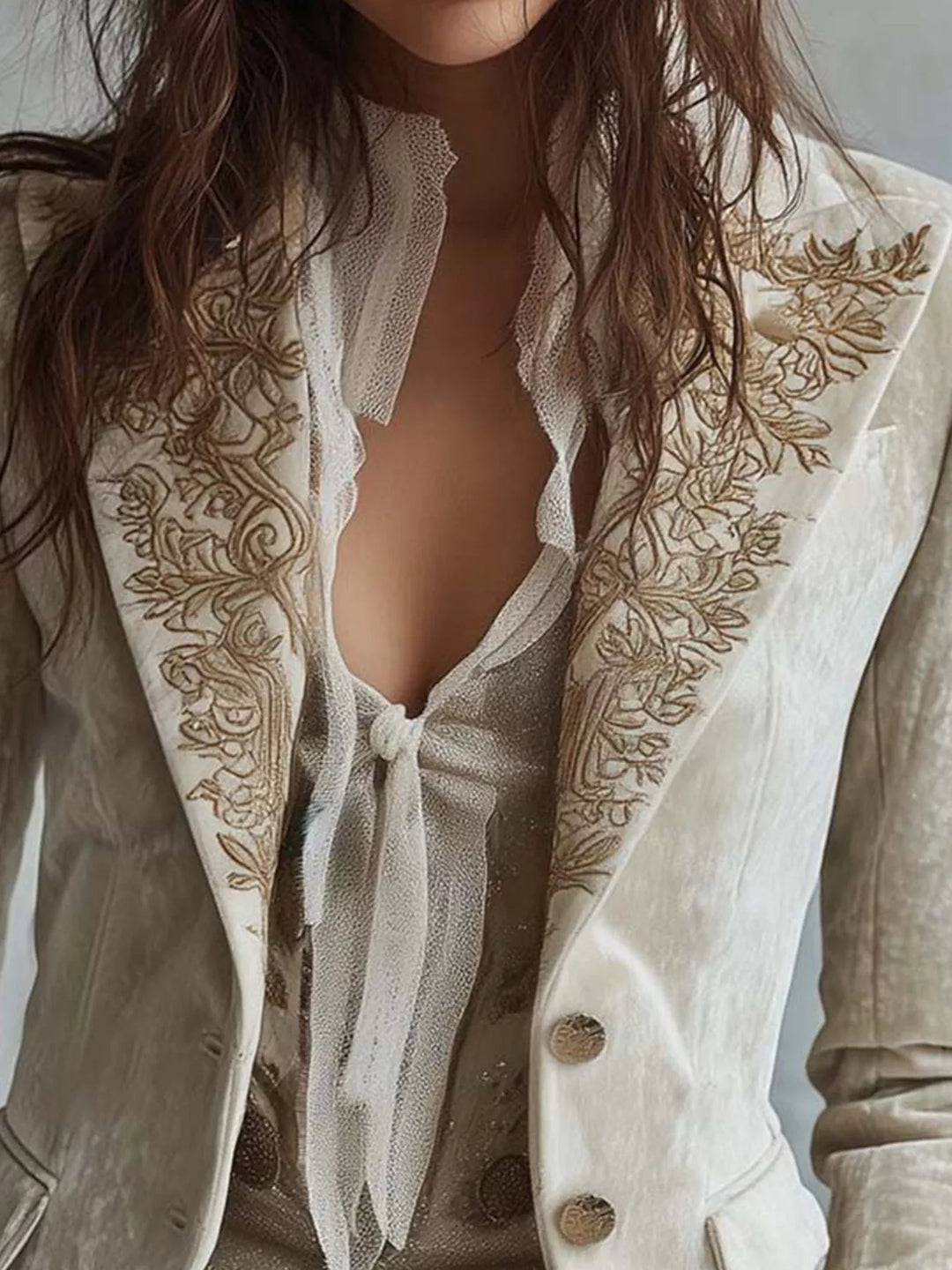 Close-up of the embroidered lapels and buttons on the cream fitted blazer