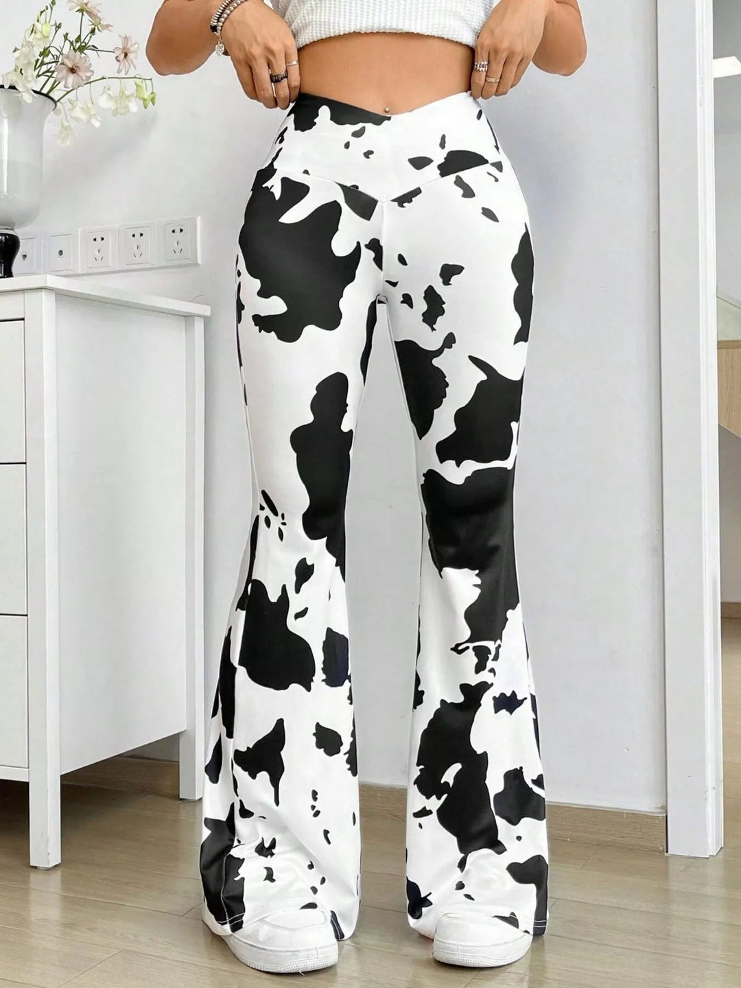 Cow print high waisted flare pants with V waistband, close front view