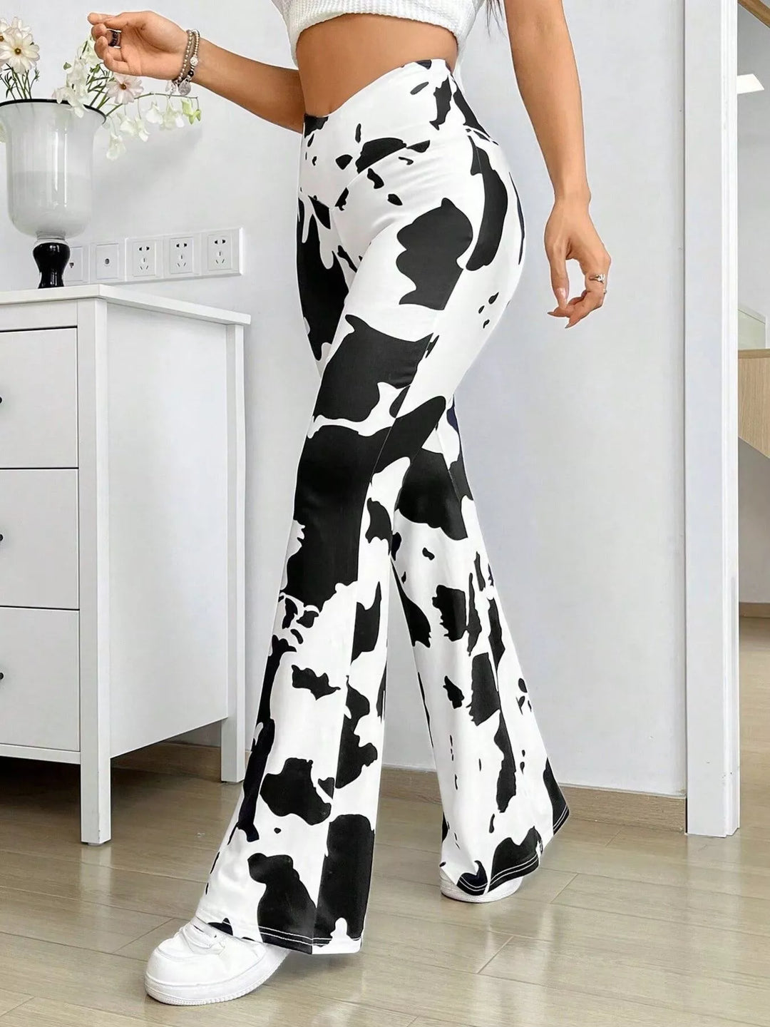 Side view of the cow print flare pants with white sneakers