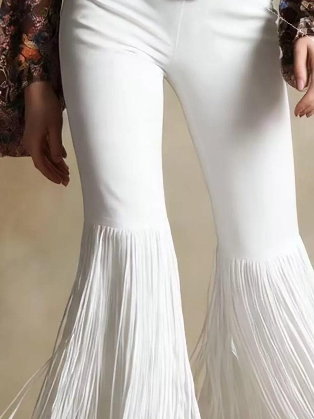 Close-up of the white flare pants and layered fringe at the hem
