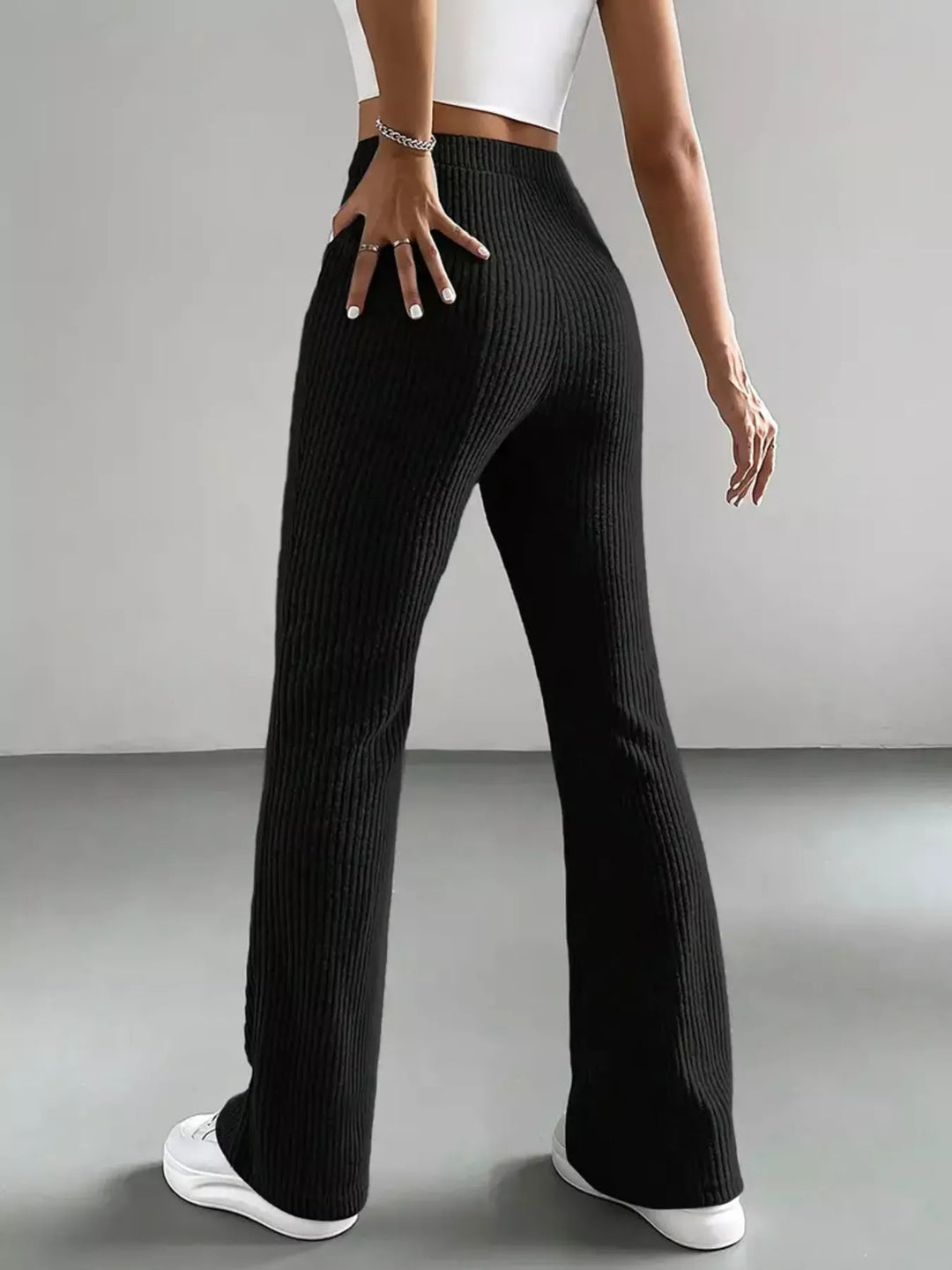 Back view of black ribbed flare pants with hand on hip