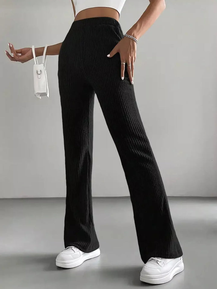 Black flare pants front view with relaxed arm pose and white sneakers