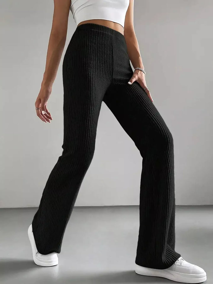 Black high waisted flare pants with white crop top and sneakers, side pose