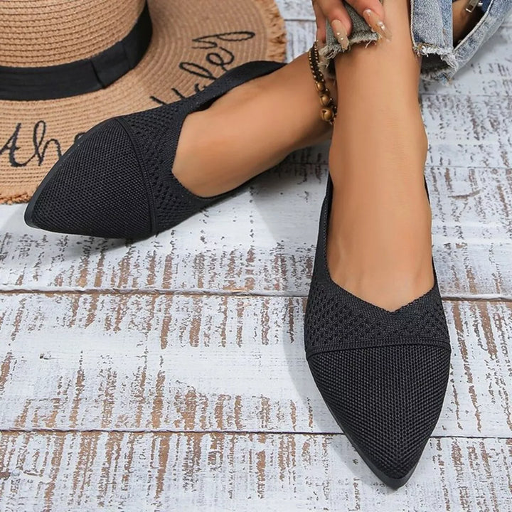 Black pointed toe knit flats, angled view of both shoes on a wood floor