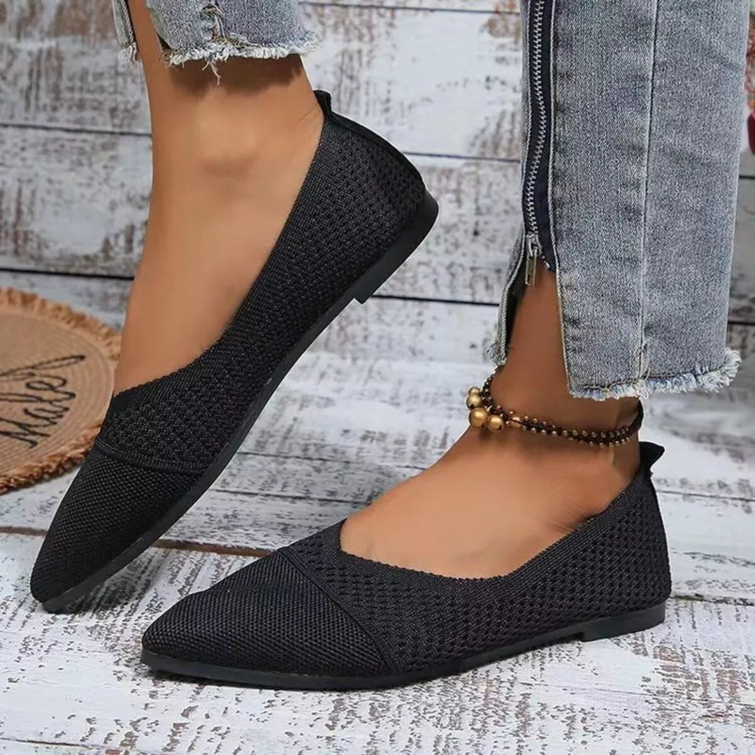 Women's flats in black, pointed toe knit slip on, worn on feet beside jeans