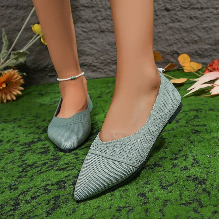 Sage knit flats with a V cut front, three-quarter view on grass