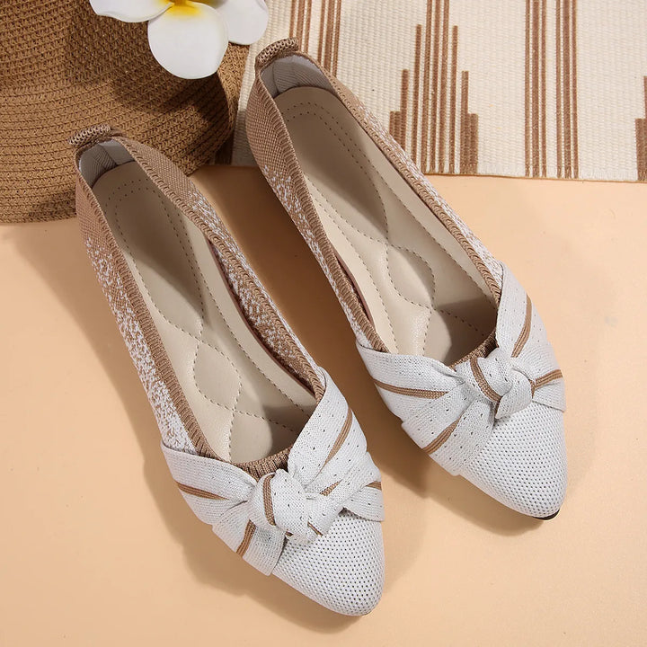 Pair of white slip on flats with a bow knot at the toe