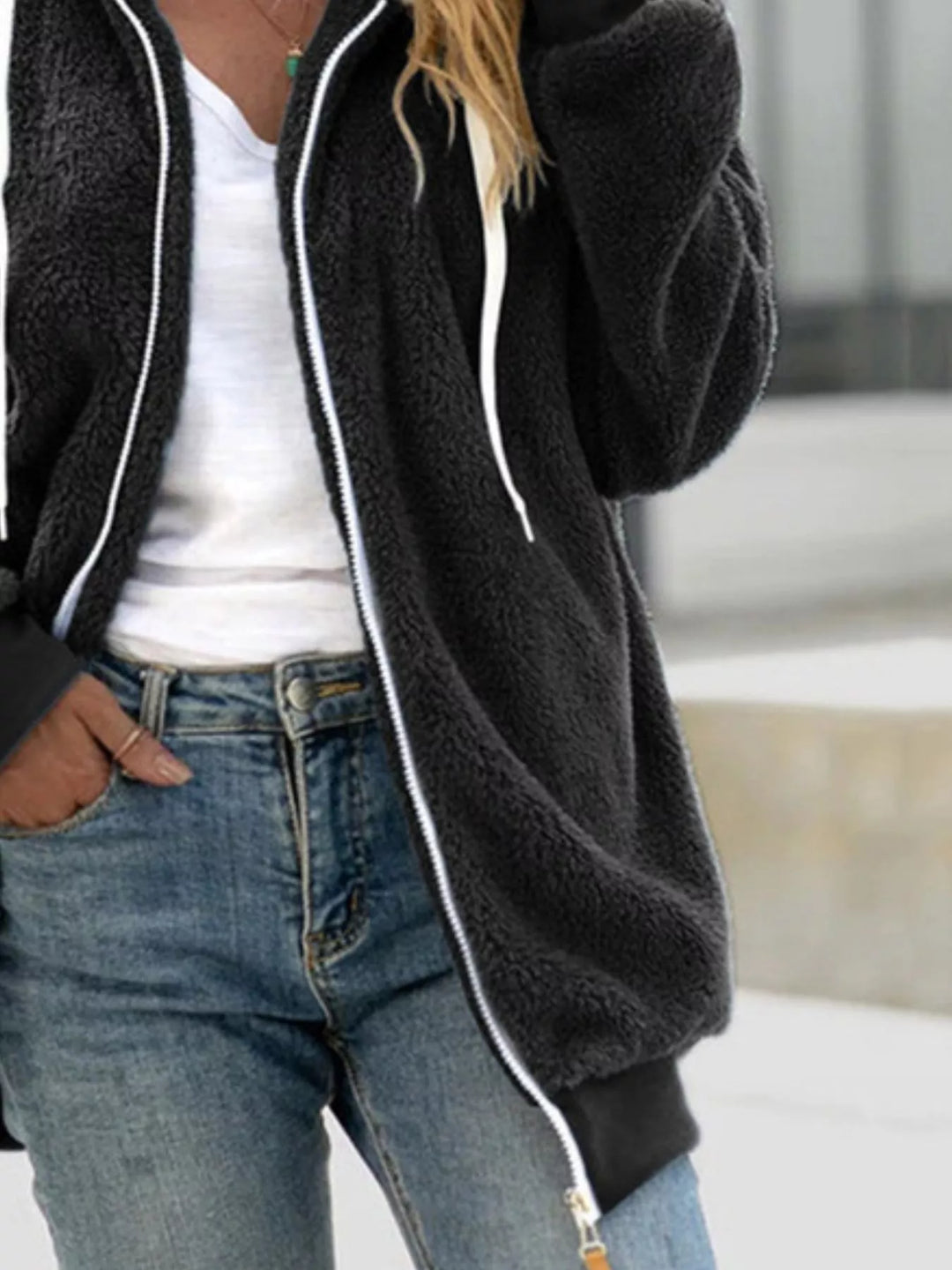 Black fleece zip up jacket, relaxed side view with hand in pocket