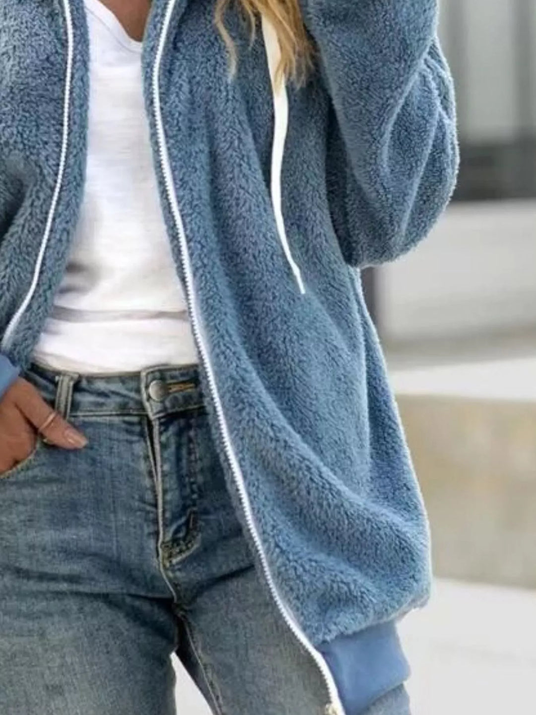 Dusty blue zip up fleece jacket with hood, relaxed side view, hand in pocket