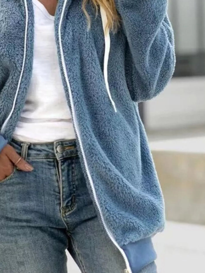 Dusty blue zip up fleece jacket with hood, relaxed side view, hand in pocket