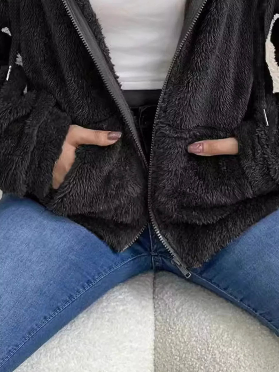Detail of black fleece jacket with hand in the front pocket and fuzzy texture