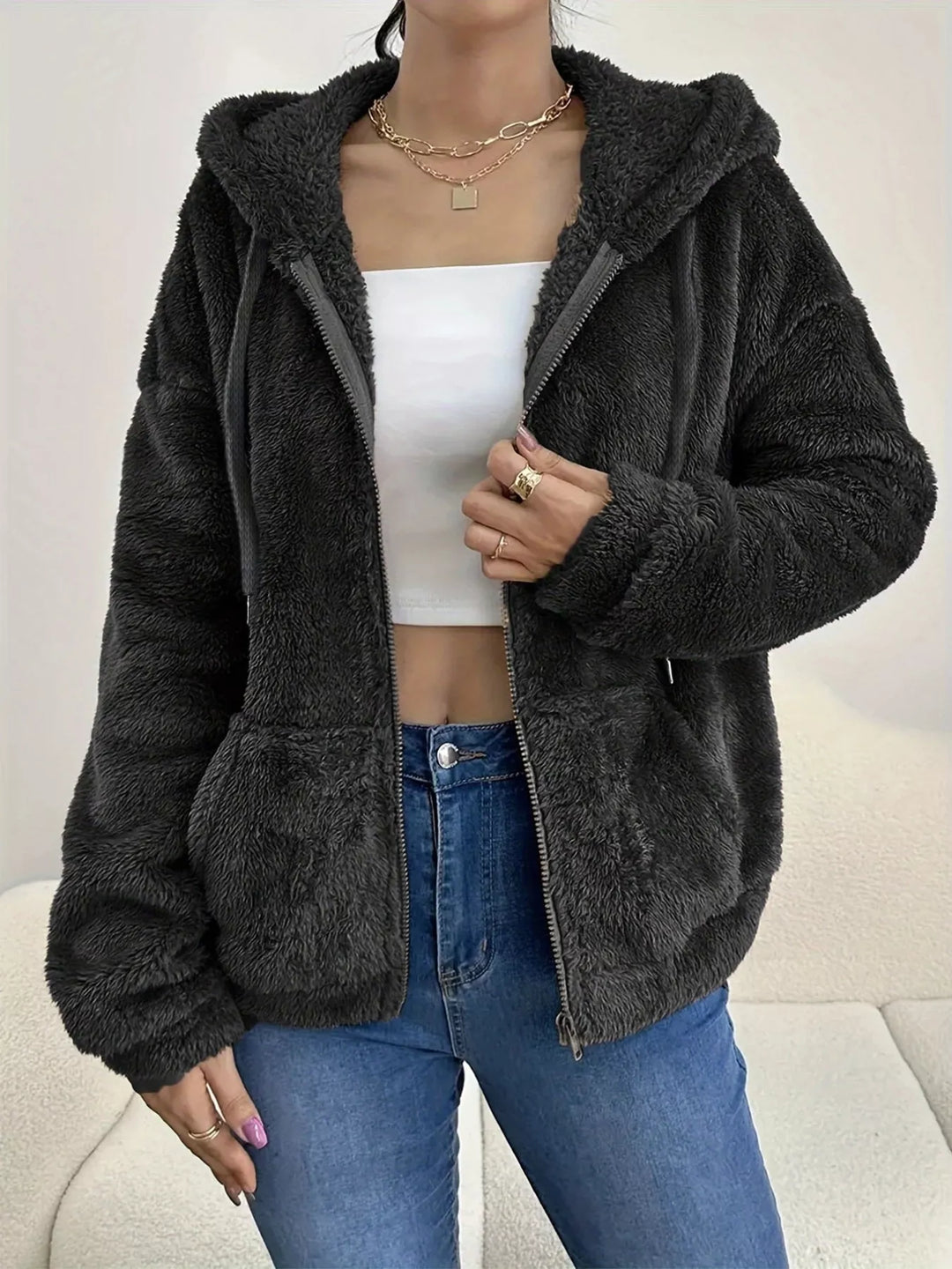 Black hooded zip up fleece jacket with drawstring hood over a white top and jeans