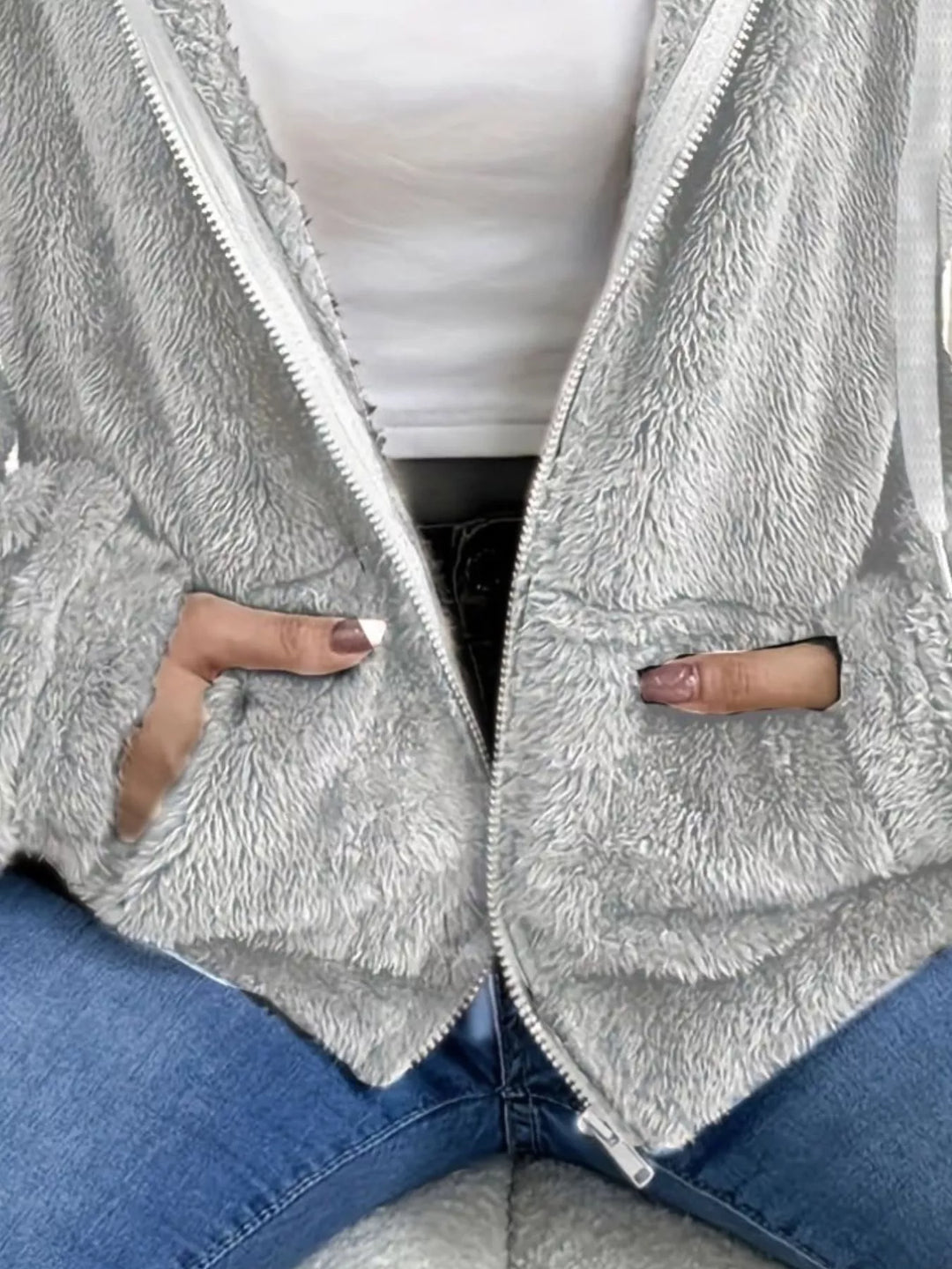 Detail of light gray fleece jacket with hand in the front pocket and fuzzy texture