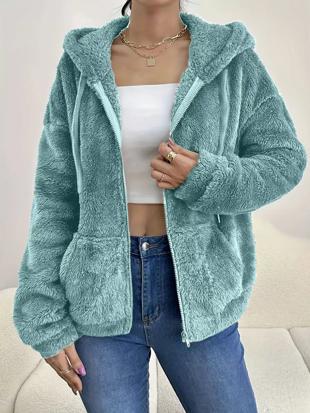 Seafoam hooded zip up fleece jacket with drawstring hood over a white top and jeans