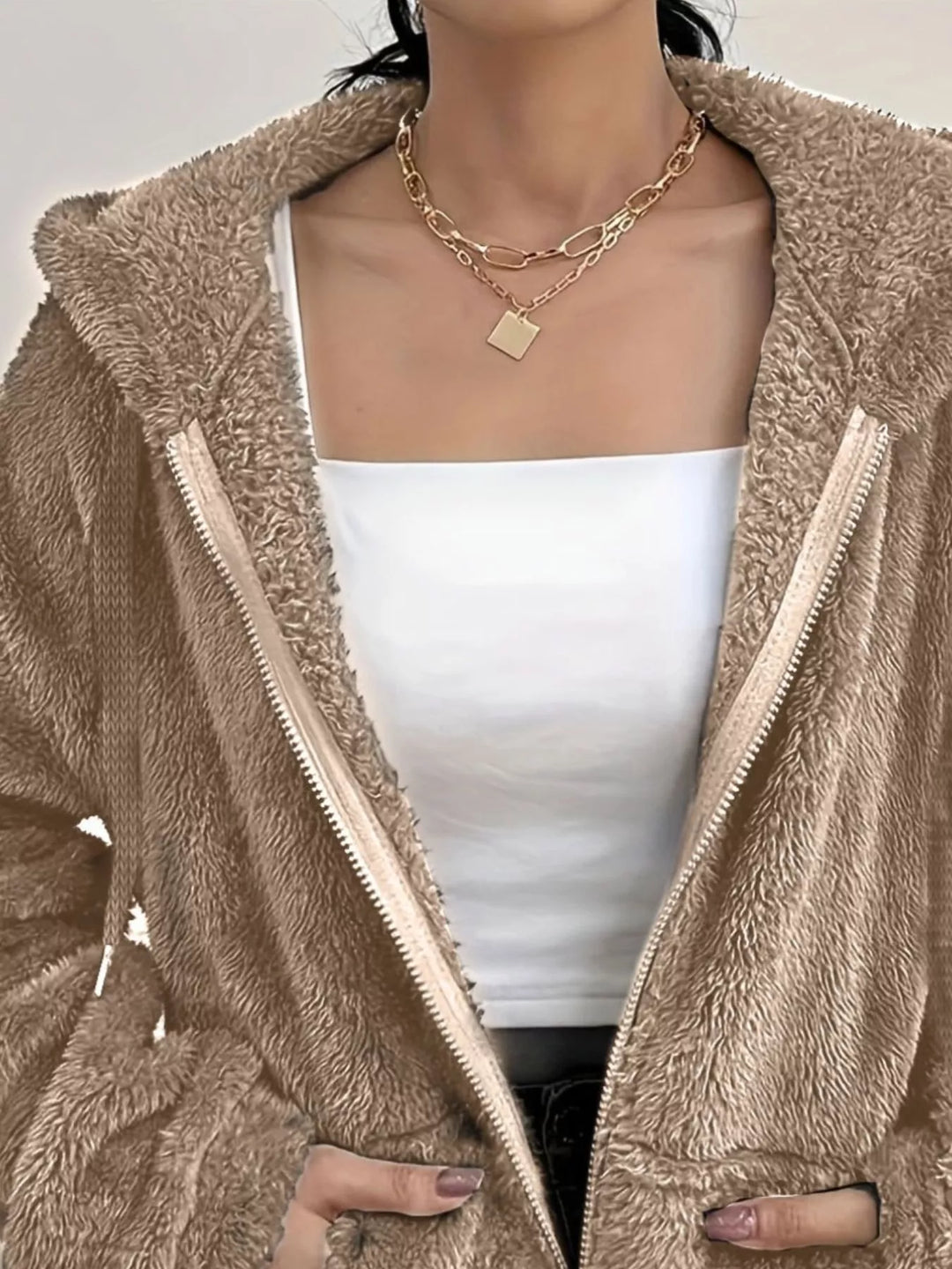 Detail of taupe fleece jacket with hand in the front pocket and fuzzy texture