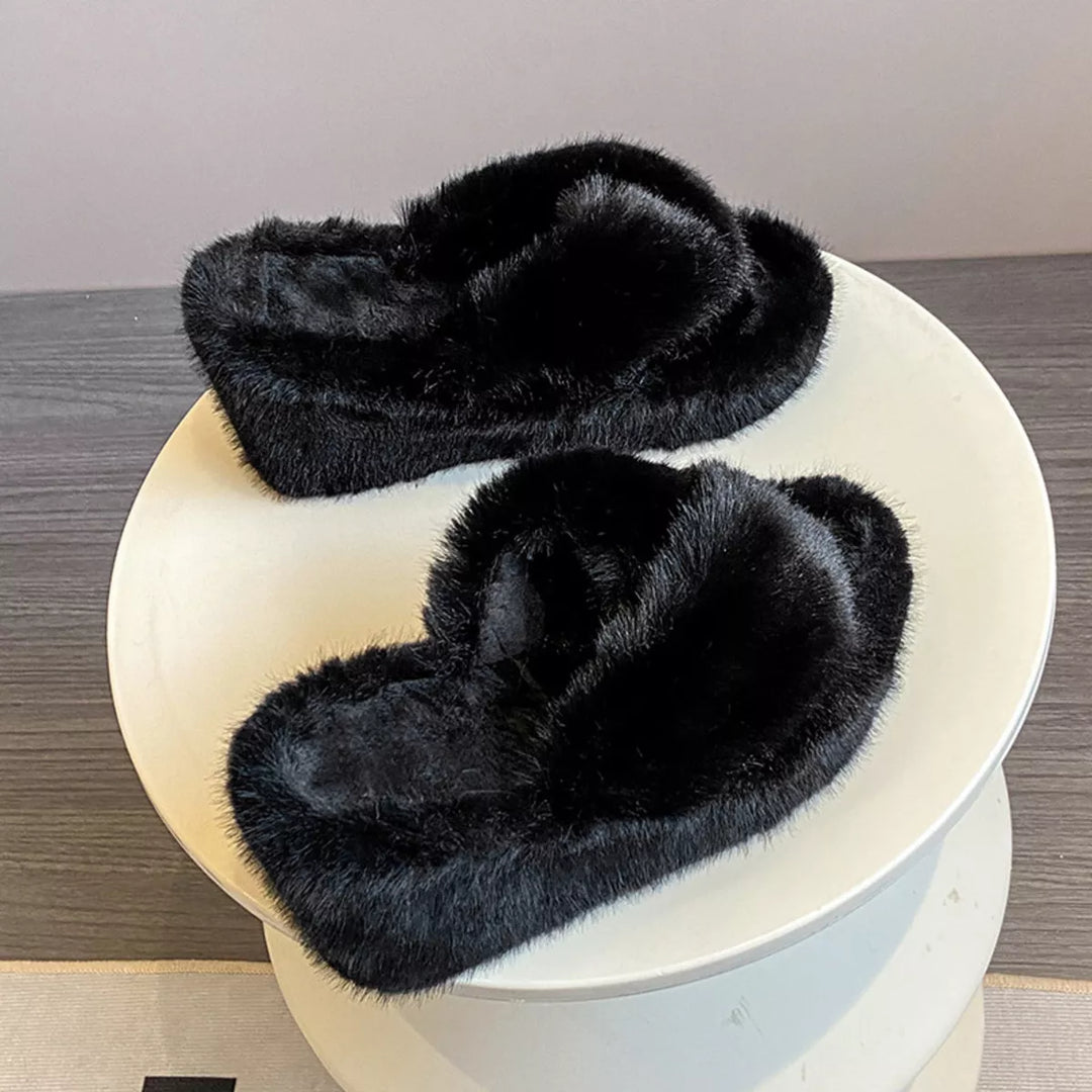 Black fluffy crossed strap platform slides placed on a white round stand