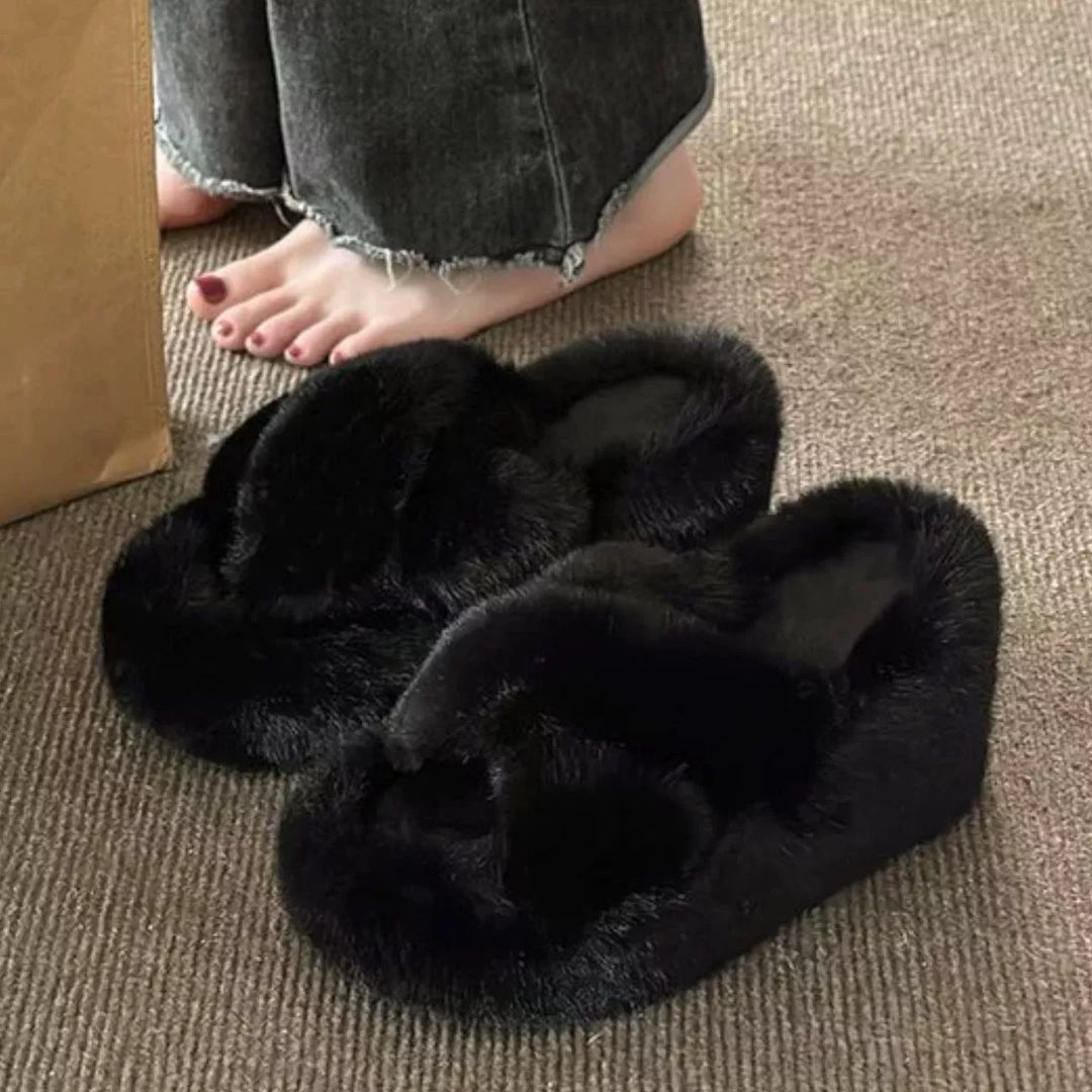 Women's fluffy slippers in black, wedge platform slides with crossed straps, on carpet